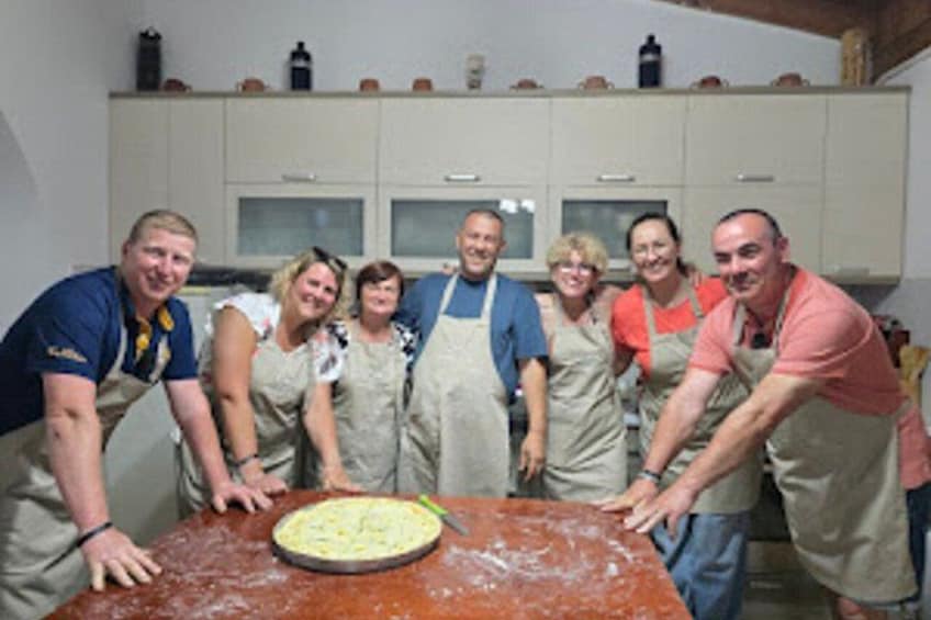 A group of people in a kitchen with a pie on the table. 5