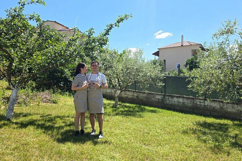 Two people standing in a grassy area with trees and a building in the background. 5