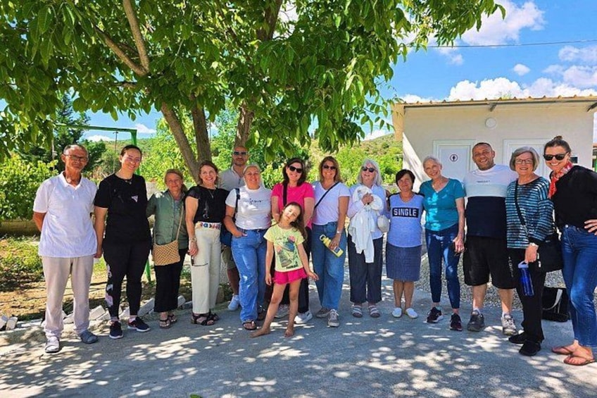 A group of people standing under a tree in an outdoor setting. 1