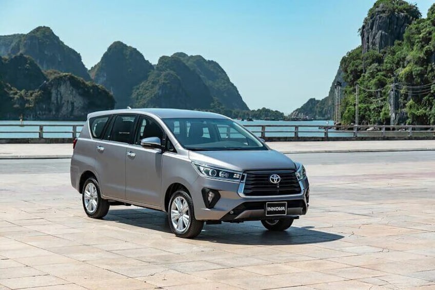 En sølvgrå Toyota Innova SUV parkeret på en belagt plads med en naturskøn bjergbaggrund. 2