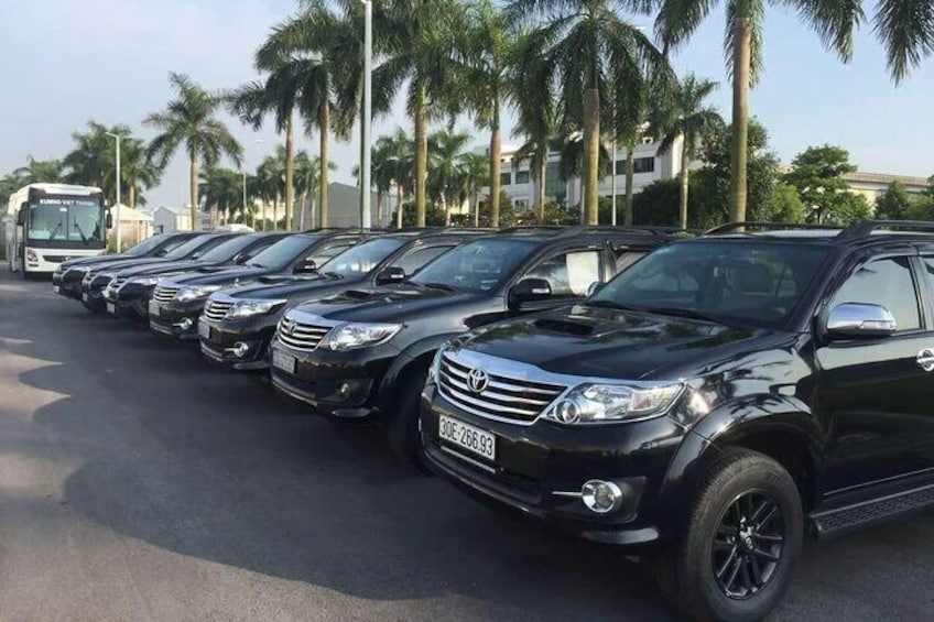 En række sorte Toyota SUV'er parkeret på en vej med palmer i baggrunden. 1