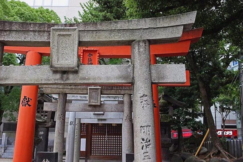 A traditional Japanese torii gate with red pillars and a stone base, surrounded by trees. 2