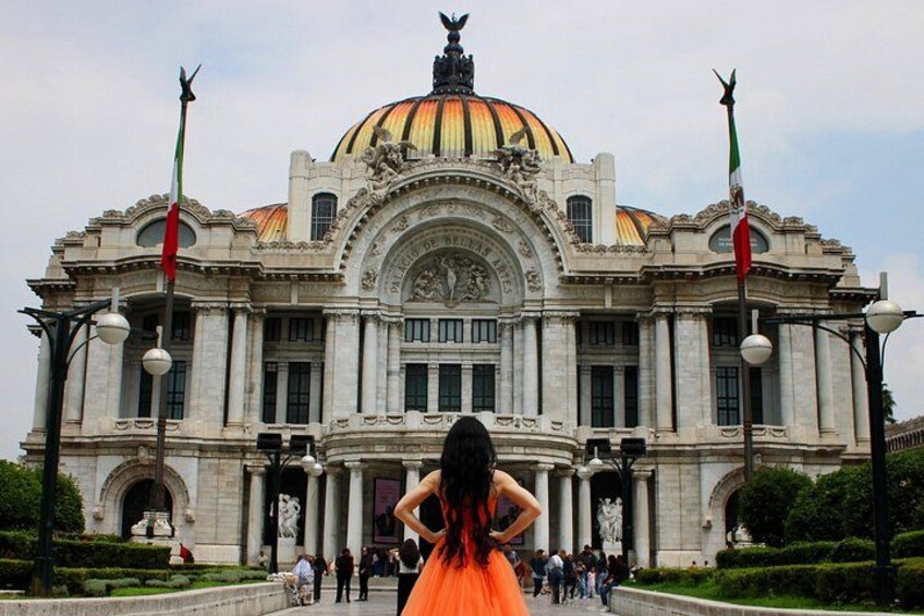 A grand building with a large dome, statues, and flags. 1