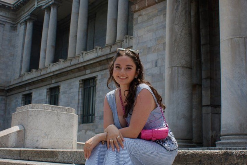 A person sitting on steps in front of a classical building with columns. 3