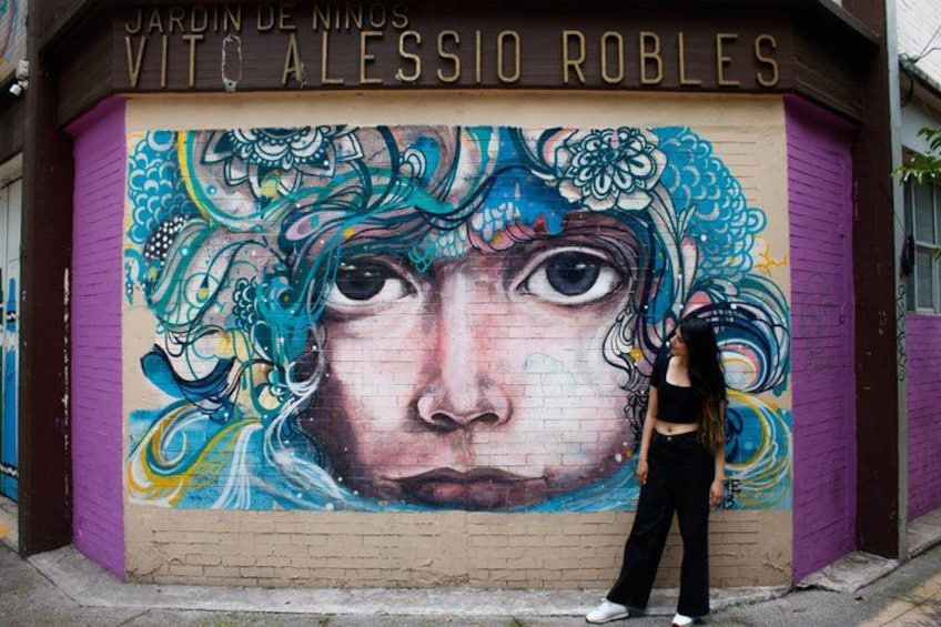 A mural on a brick wall with a person standing in front of it. 2