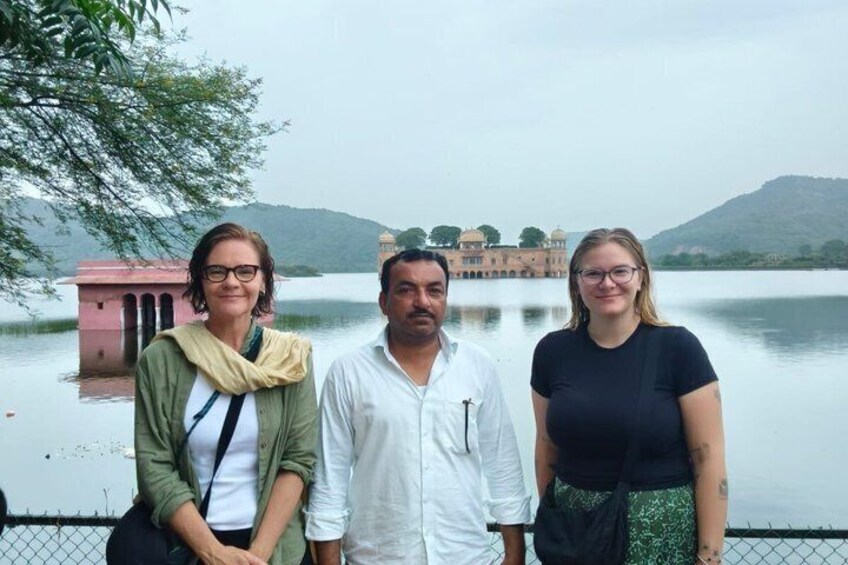 Three people standing by a lake with a building in the background. 2