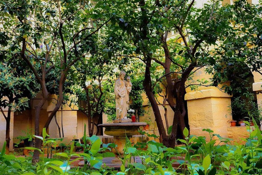 A garden with a statue, trees, and potted plants. 3