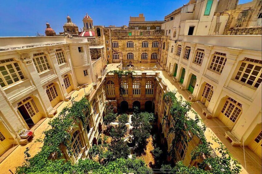 A courtyard with buildings, a fountain, and greenery. 1