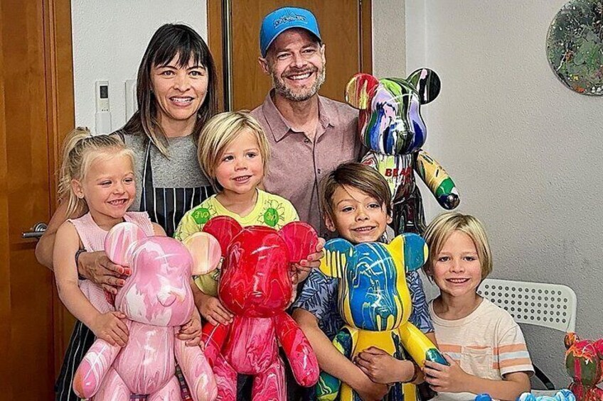 A family with children holding plush toys, a man in a cap, and a colorful robot figure. 1