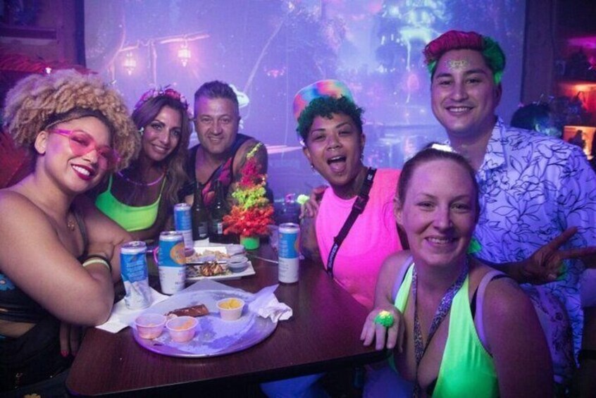 A group of people at a party with a table full of snacks and drinks. 4