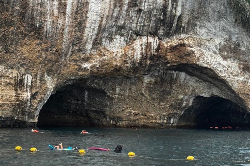 A cave entrance with water and people swimming. 4
