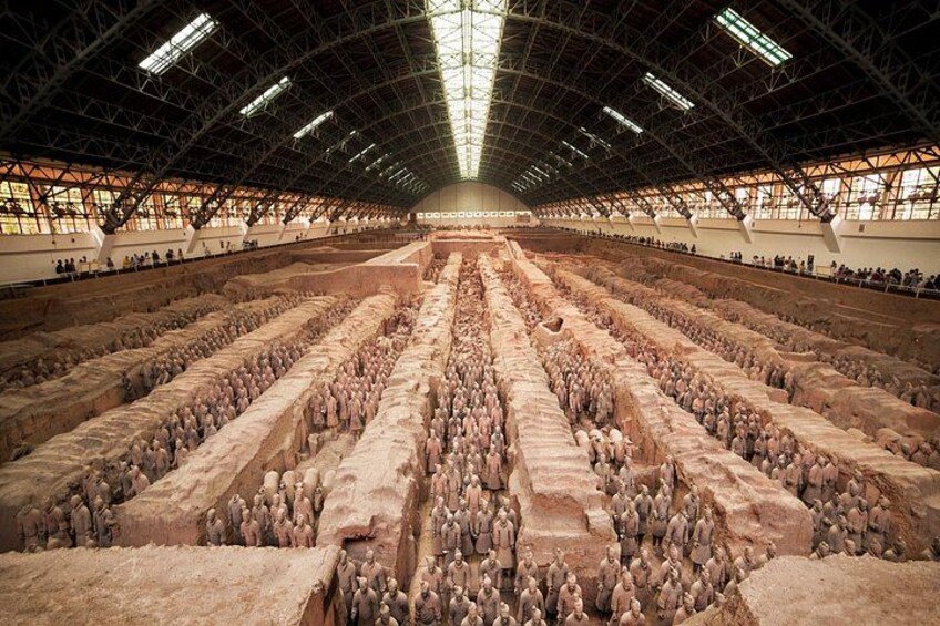 A large indoor space with rows of terracotta soldiers arranged in a formation. 3