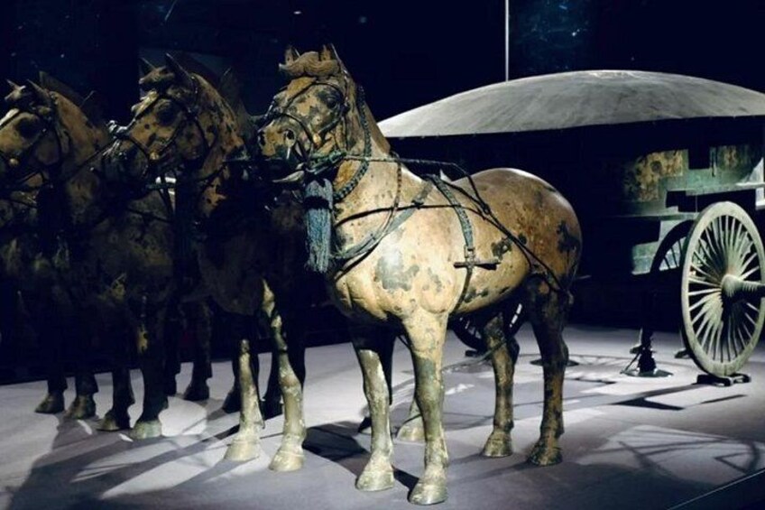 A collection of bronze horse-drawn chariots with a large wheel. 2