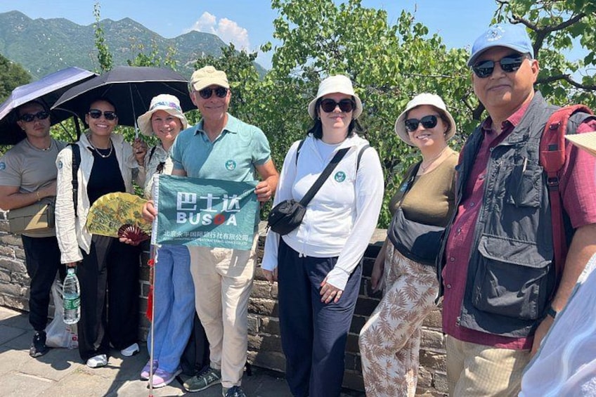 A group of people standing on a stone wall with a mountainous landscape in the background. 2