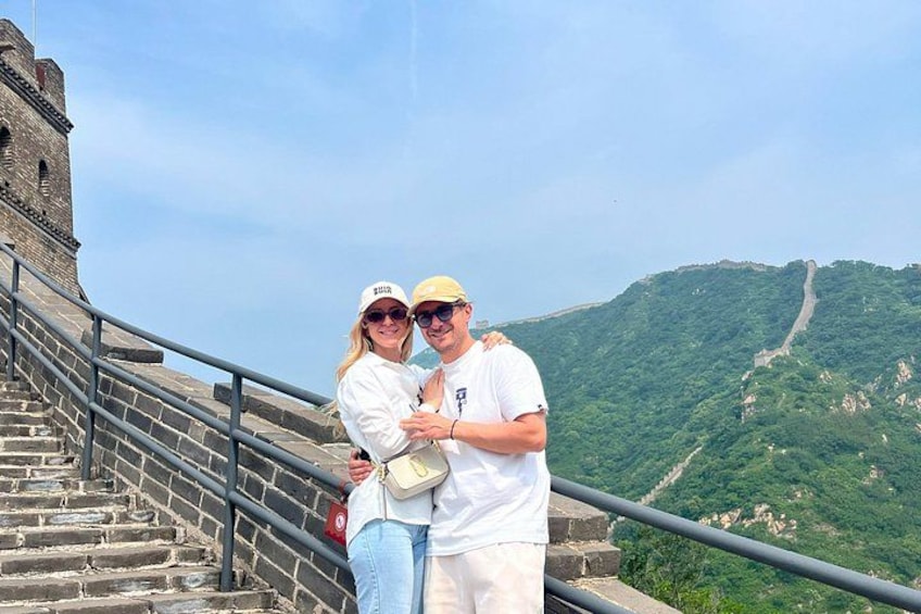 A couple embracing on the Great Wall of China with a mountainous landscape in the background. 4