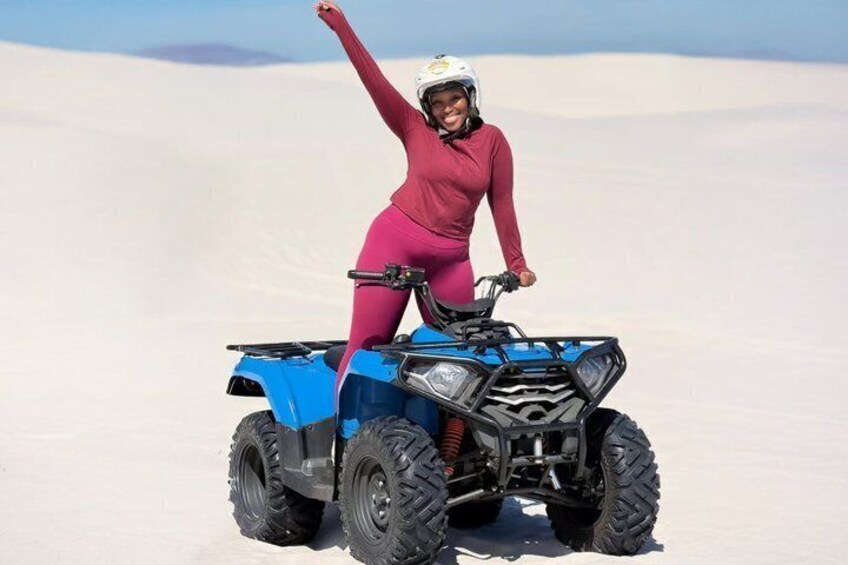 Una persona en un vehículo todo terreno azul en un desierto con dunas de arena. 1