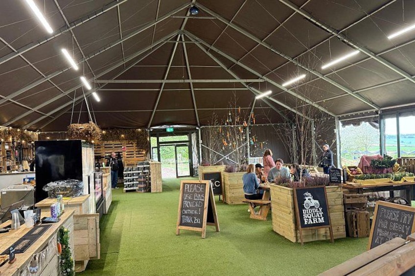 An indoor market with wooden stalls, green carpet, and chalkboard signs. 2