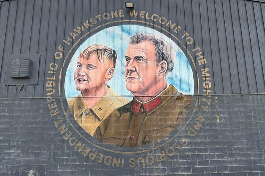 A mural on a building wall with a circular design and text. 3