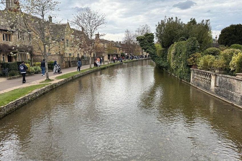 A canal with people walking along the banks, surrounded by historic buildings and trees. 5