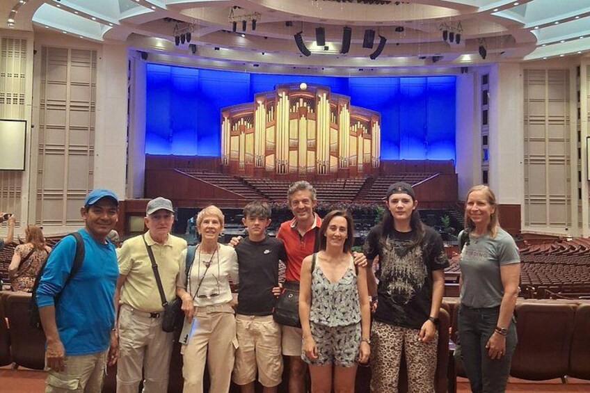 A group of people standing in a theater with a stage and seating area. 3