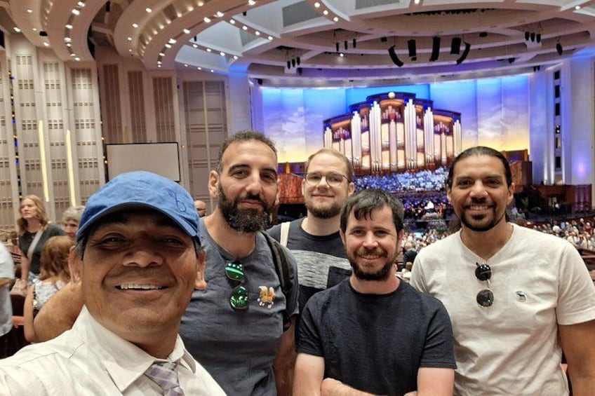 A group of people in a concert hall with a large organ in the background. 4