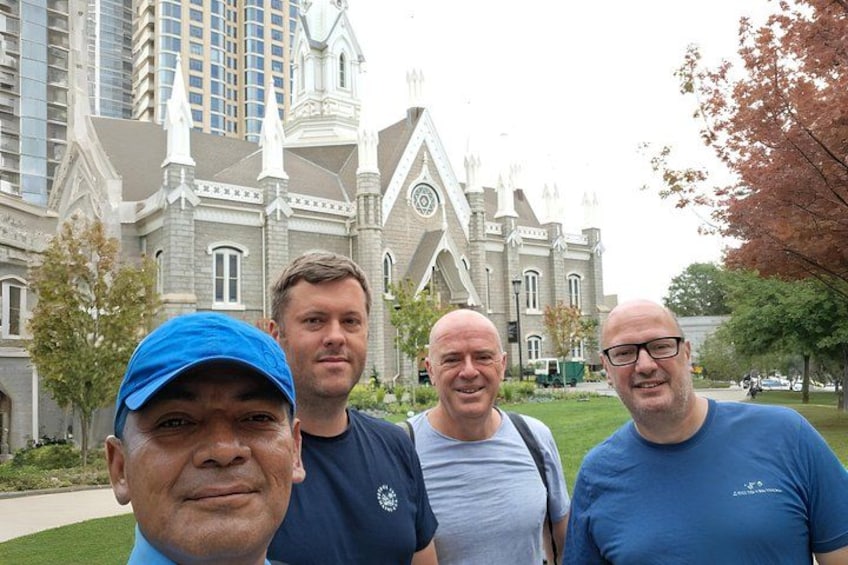 Four people standing in front of a large, historic building with a clock tower. 2