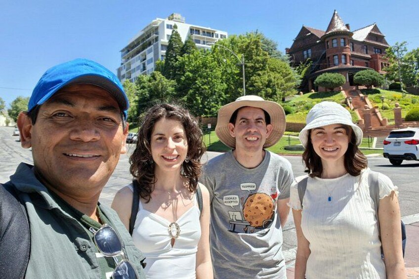 Four people standing on a street with a large building in the background. 1
