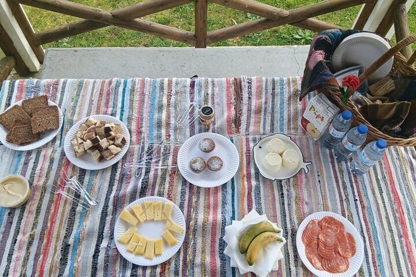 A picnic setup with various food items and drinks on a striped tablecloth. 3