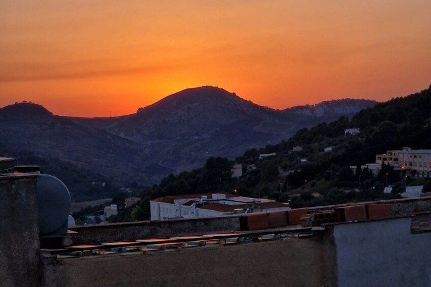 A sunset over a mountainous landscape with buildings in the foreground. 2