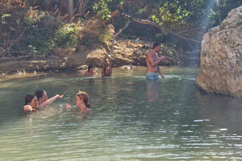 People swimming in a natural water body surrounded by rocks and vegetation. 5