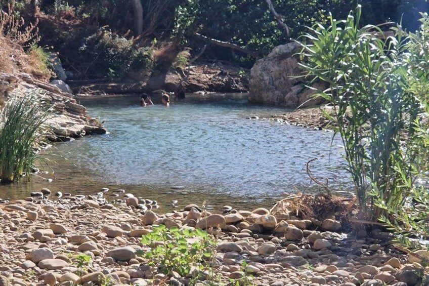 A rocky riverbank with a clear stream, surrounded by greenery and rocks. 4