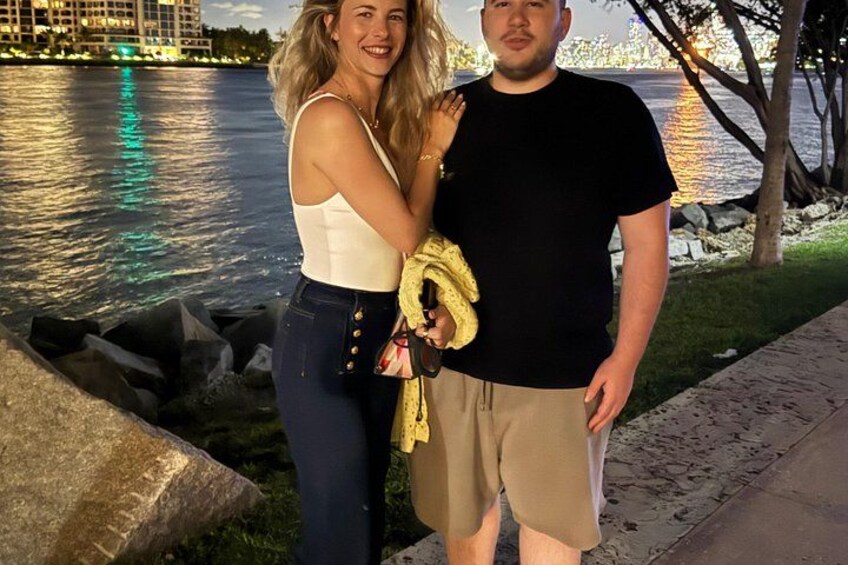 Two people standing by a waterfront with a city skyline in the background. 5