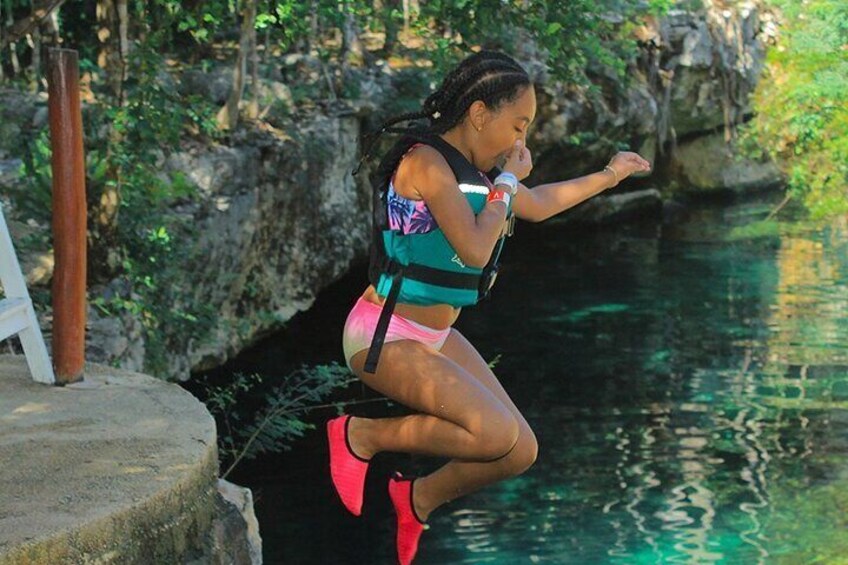 A person jumping into a body of water surrounded by greenery and rocks. 4