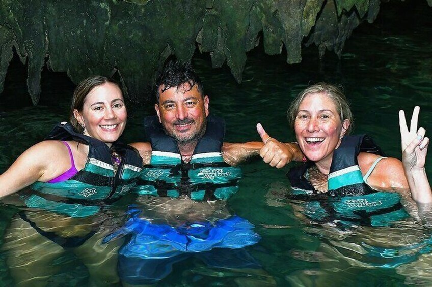 Three people in a cave with water, wearing life jackets. 3