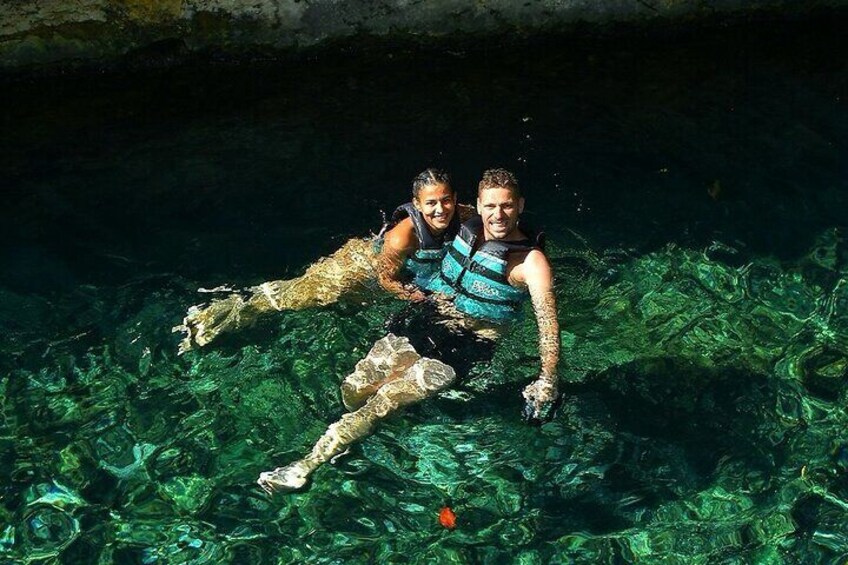 Two people swimming in clear water with visible underwater rocks and formations. 5