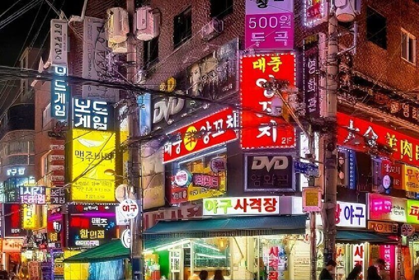 Une rue animée en ville, illuminée de mille feux la nuit, avec de nombreuses enseignes et publicités colorées. 3