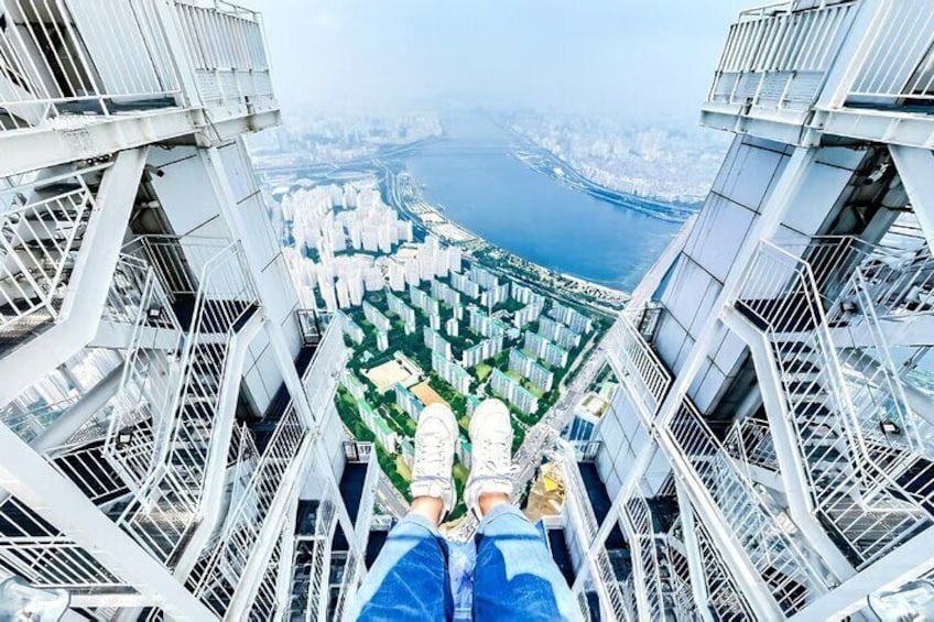 Une personne assise sur un balcon élevé, d’où l’on peut admirer un paysage urbain et une étendue d’eau. 4