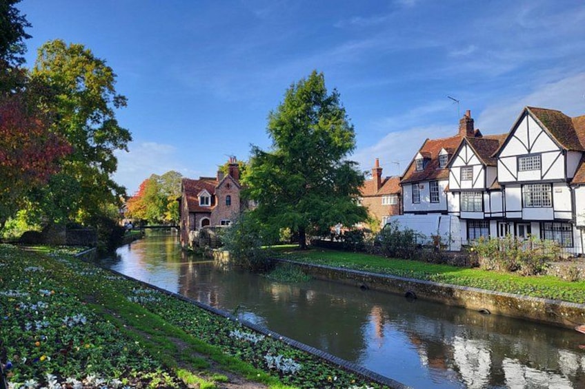 A river with houses on the right bank, a tree in the foreground, and a clear sky. 5