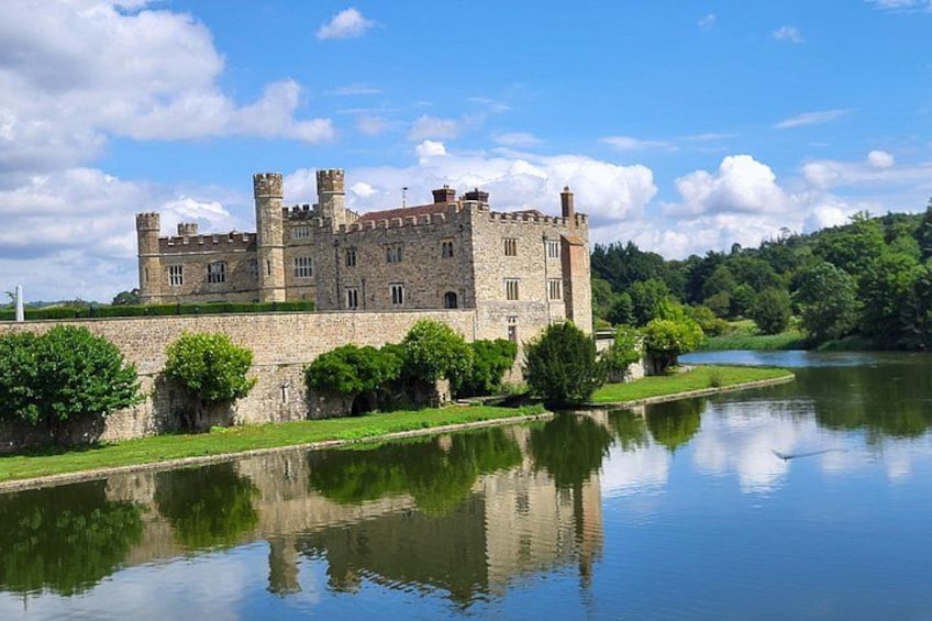 A castle with a moat, surrounded by greenery and a clear sky. 4
