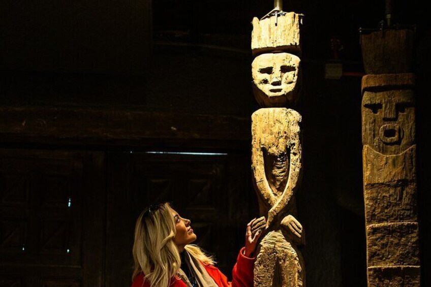 Una persona contemplando antiguas esculturas de piedra en una habitación tenuemente iluminada. 5