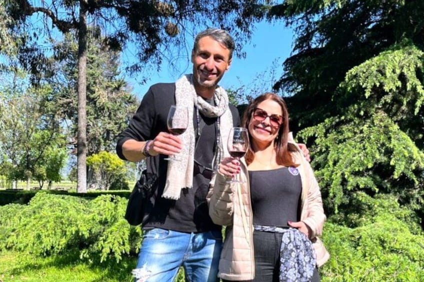 Two people standing outdoors, one holding a wine glass. 3