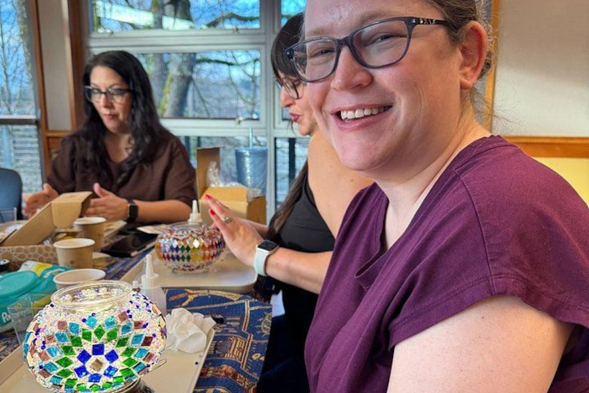 A person holding a colorful mosaic bowl, with another person in the background. 2