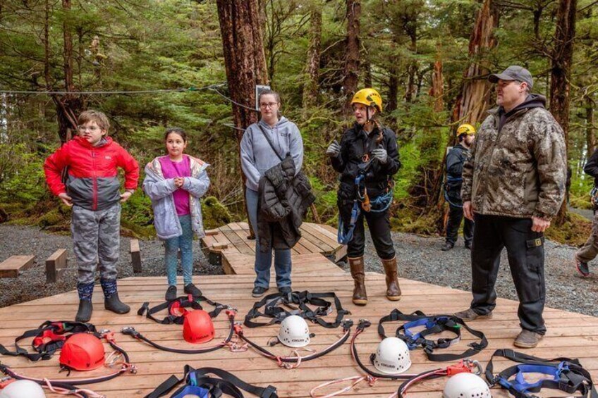 A group of people in a forested area with hiking gear and helmets laid out on the ground. 4