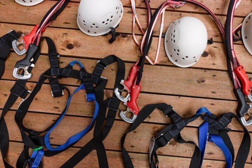 A collection of helmets and harnesses on a wooden surface. 5