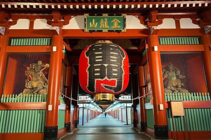 A traditional Japanese torii gate with a large red lantern and a green sign above it. 3