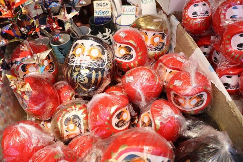 A collection of traditional Japanese dolls, some wrapped in plastic, displayed in a box. 2
