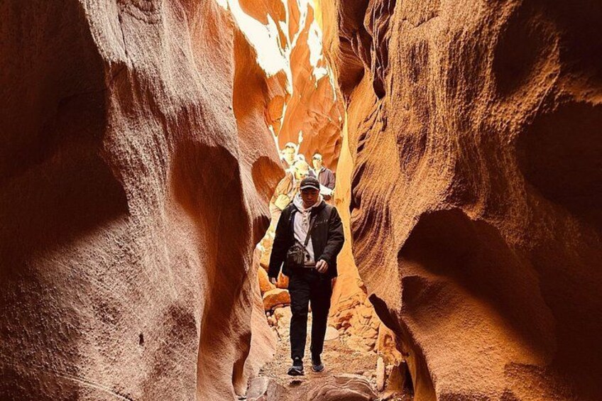 A person standing in a narrow canyon with red rock walls. 4