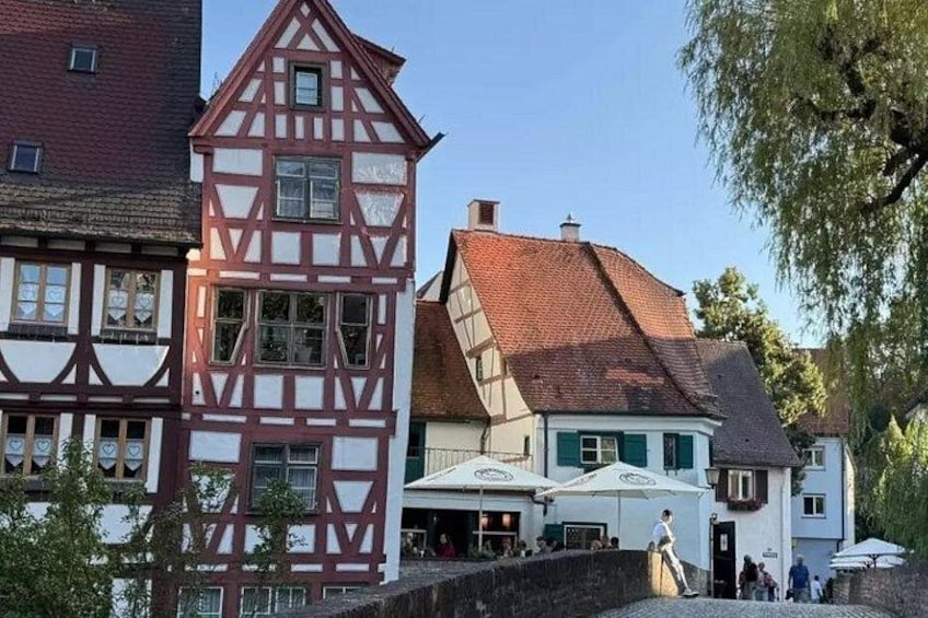 A traditional half-timbered building, a cobblestone street, and a small outdoor seating area with umbrellas. 2