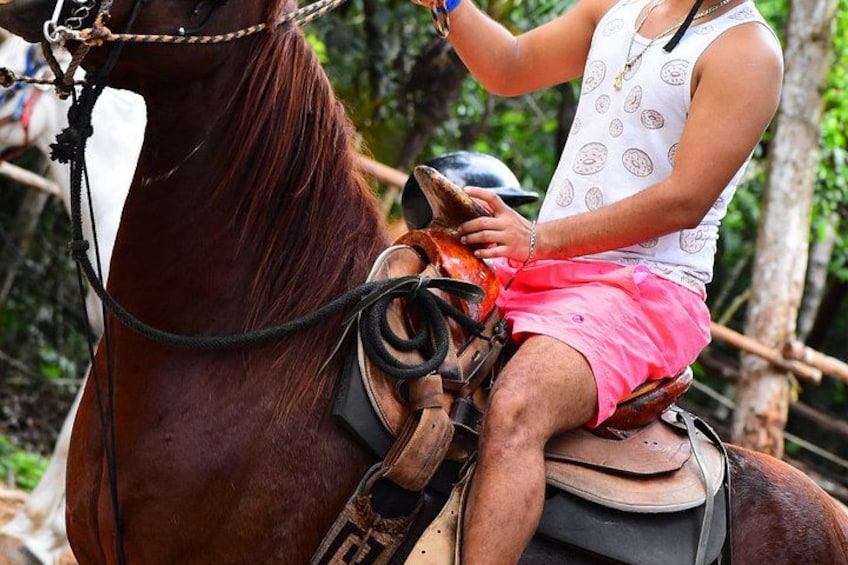 A person riding a horse, wearing a white sleeveless top and pink shorts, with a saddle and reins visible. 2