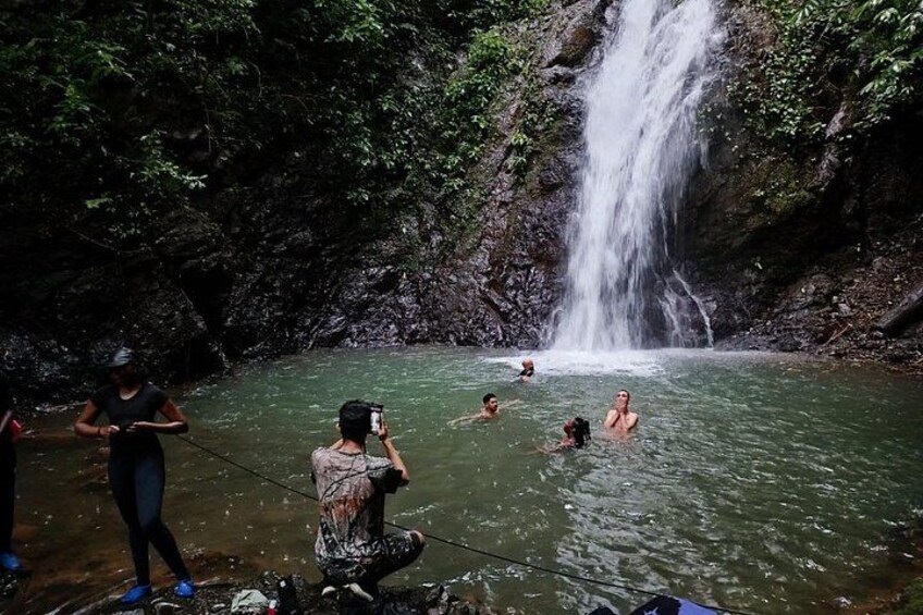 A waterfall, people swimming, and a person taking a photo. 5